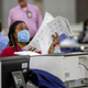 Fulton County employee Shaye Moss scans mail-in paper ballots at the Georgia World Congress Center during the Georgia primary elections in Atlanta on Tuesday, June 9, 2020. Two Georgia election workers have filed a defamation lawsuit against a conservative website, filed Thursday, Dec. 2, 2021.